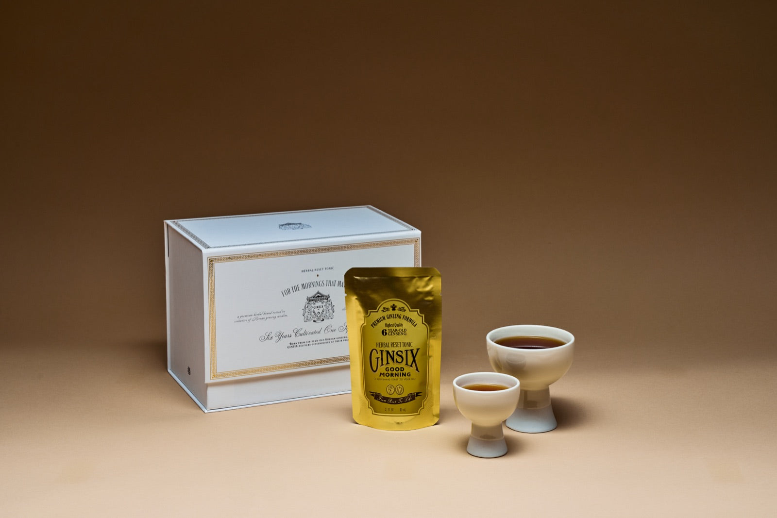 GINSIX gift box and gold tonic pouch beside the six-year ginseng root